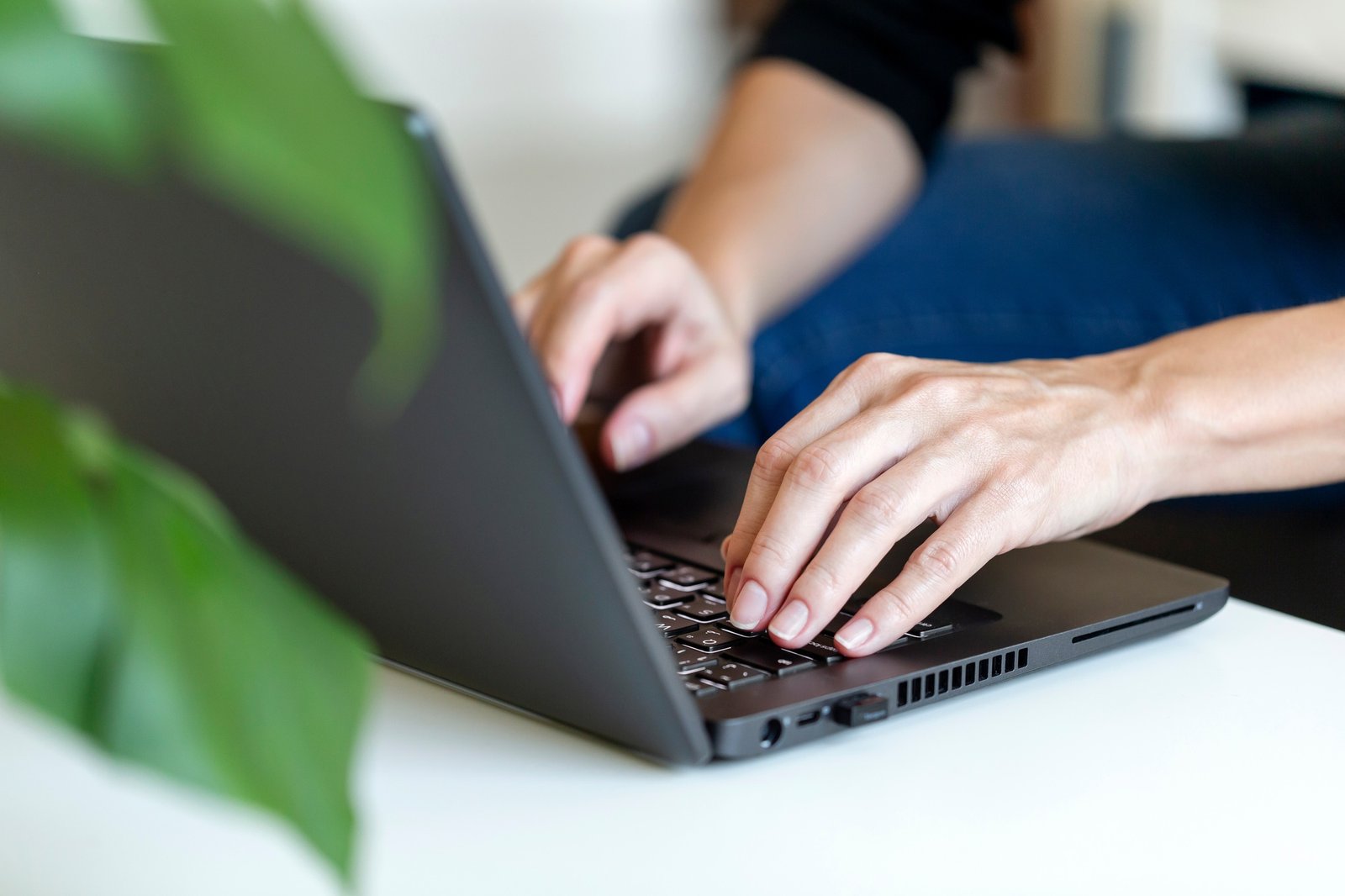 Freelancer working from home on laptop. Hands typing on keyboard, closeup.